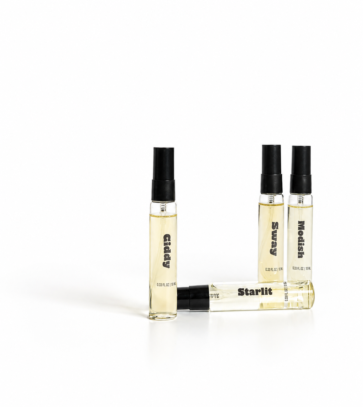 Four clear glass perfume sample vials with black spray caps, containing a pale yellow liquid, arranged on a white background. Three vials stand upright and one lies horizontal in front, with printed text including 'Gisly', 'Starlit', and 'Needle'.